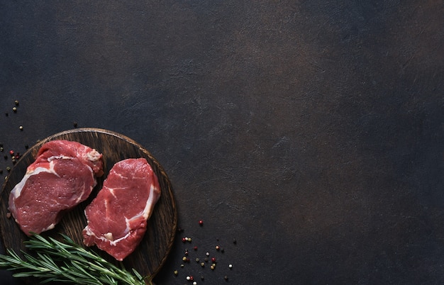 Filete de ternera chuletón de cocción cruda con frambuesa sobre una tabla de madera. Vista superior con espacio de copia.