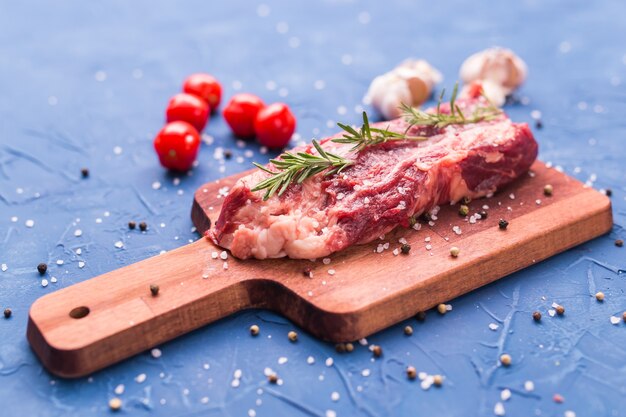 Filete de ternera cruda con hierbas y especias sobre fondo de madera