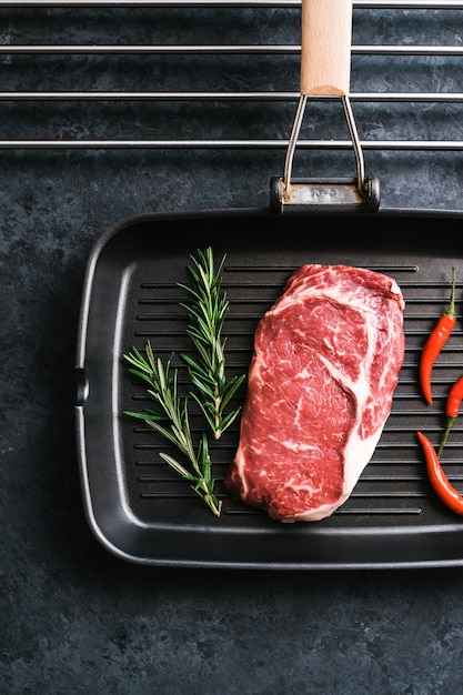 Filete de ternera cruda rib eye en sartén negra para asar con ají y romero