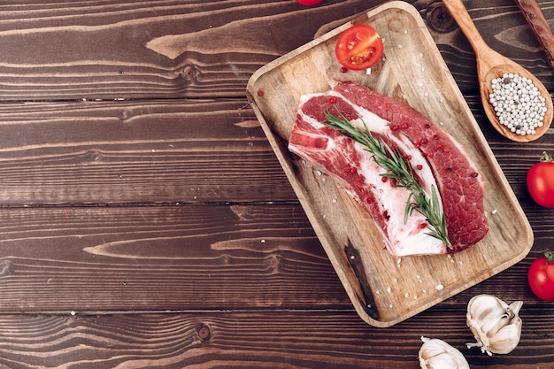 Filete de ternera cruda con romero y especias sobre tabla de madera