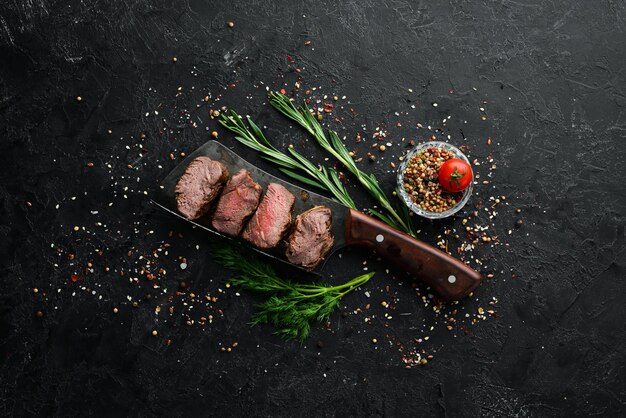 Filete de ternera con cuchillo sobre fondo de piedra negra Vista superior Espacio libre para el texto