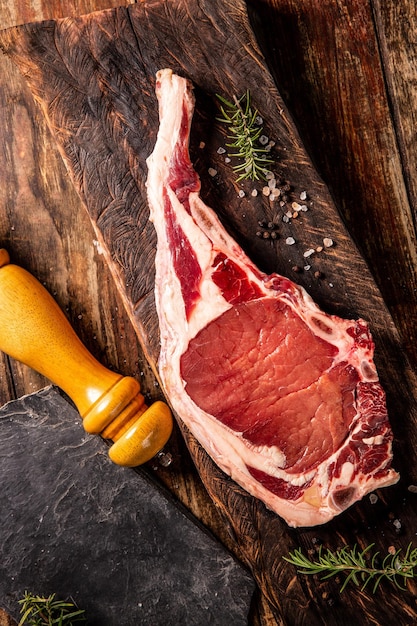 Filete de ternera fresca tomahawk para parrilla o barbacoa en madera con sal y pimienta negra Adorne con romero Vista superior Día mundial de la alimentación