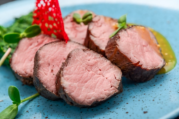 Filete de ternera jugoso con salsa de espinacas y mostaza sobre una superficie negra