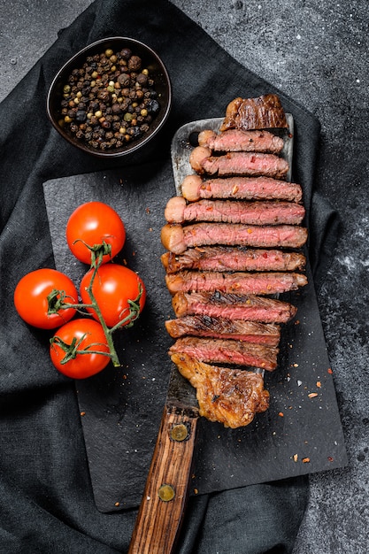 Filete de ternera marmoleado en rodajas a la parrilla en una cuchilla de carne Superficie negra. Vista superior