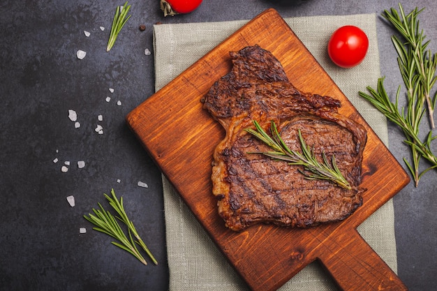 Filete de ternera a la parrilla con especias y hierbas sobre tabla de madera. Vista superior plana con espacio de copia