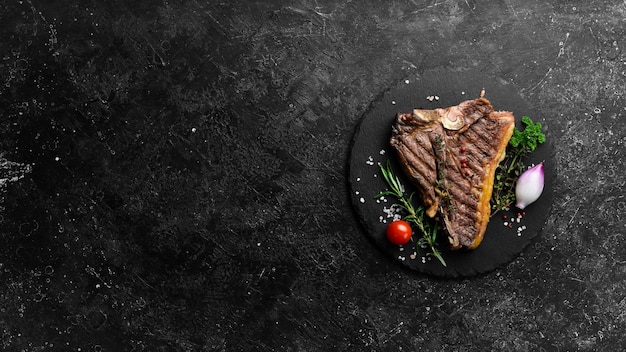 Filete de ternera a la parrilla Filete en un plato negro Vista superior Sobre un fondo de piedra negra