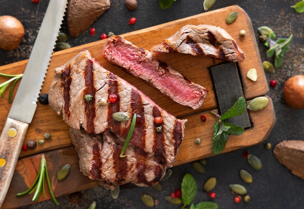 Foto filete de ternera a la parrilla con hierbas y especias en la mesa oscura de cerca