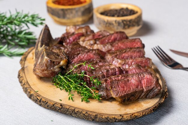 Filete de ternera a la parrilla medio raro en rodajas sobre tabla de cortar de madera con especias