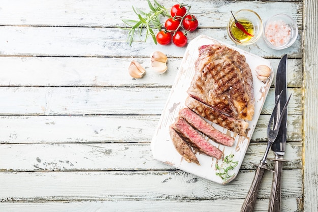 Filete de ternera a la parrilla medio raro en rodajas sobre tabla de cortar rústica con romero y especias