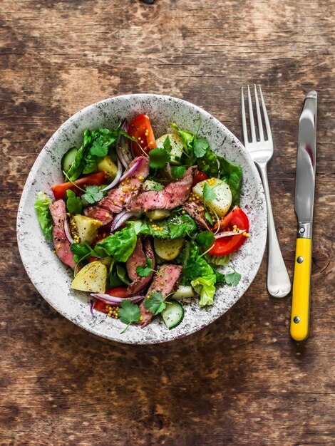 Filete de ternera con patata romana y ensalada de verduras sobre un fondo de madera vista superior Dietas equilibradas alimentos saludables