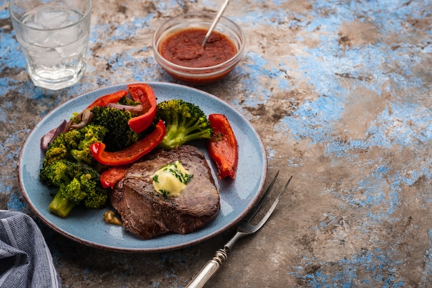 Filete de ternera a la plancha con mantequilla de ajo y verduras. carne con pimiento asado, brócoli y cebolla.