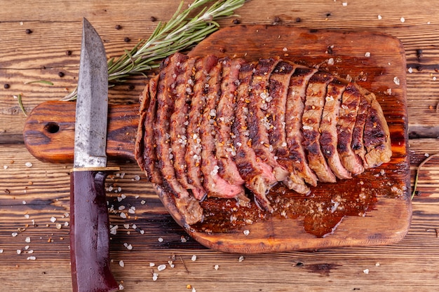 Filete de ternera a la plancha en rodajas con especias y cuchillo en tabla de cortar de madera