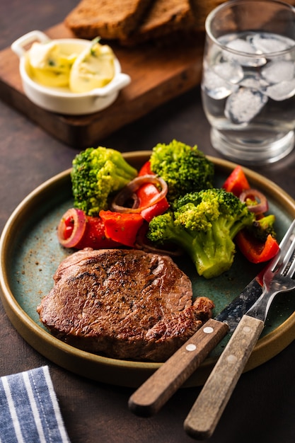 Foto filete de ternera a la plancha con verduras. carne con pimiento asado, brócoli y cebolla