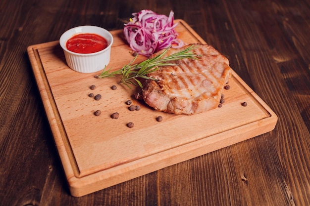 Filete de ternera con ramita de romero sobre una mesa de madera