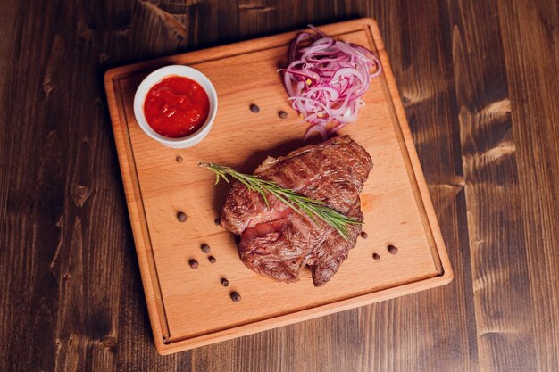 Filete de ternera con ramita de romero sobre una mesa de madera