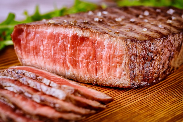 Filete de ternera raro a la parrilla en rodajas servido sobre tabla de madera.