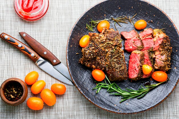 Filete de ternera en rodajas asado con kumquat, romero y especias.Entrecot de ternera en un plato