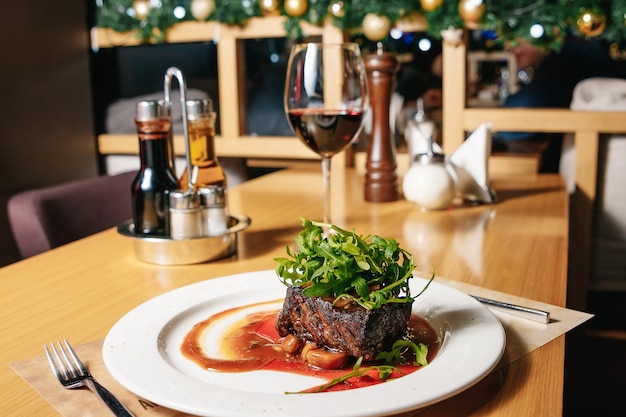 Filete de ternera con rúcula y champiñones en un plato blanco sobre la mesa en el restaurante.