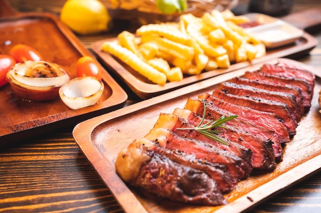 Filete de ternera servido en un plato de madera con hierbas de romero y pimienta carne fresca a la parrilla hecha para la cena picanha o solomillo de ternera cortado con sal y verduras