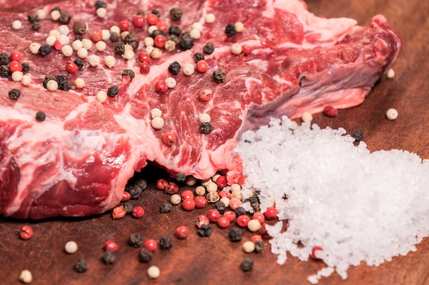 Filete de ternera en una tabla de madera con especias pimienta perejil sal cebollas chalotes ajo