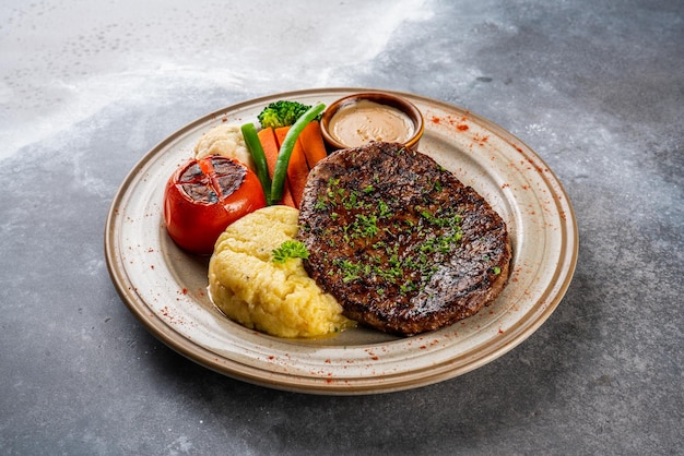 Filete de ternera con tomate servido en un plato aislado en la comida de vista lateral de fondo oscuro