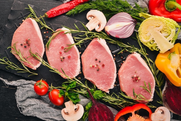 Filete de ternera con verduras frescas y romero y especias sobre un fondo de madera negra Vista superior Espacio libre para texto