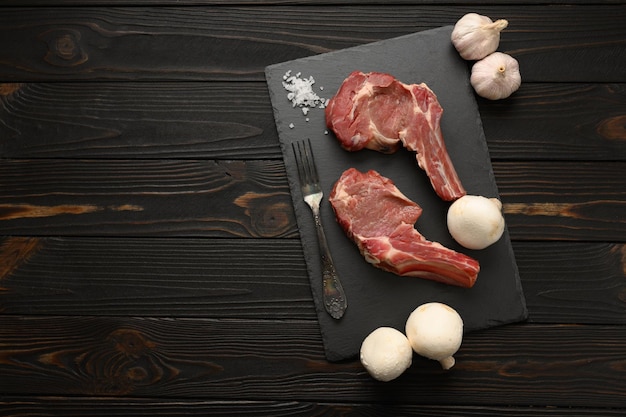 Filete de vaquero crudo y especias sobre un fondo de madera negra