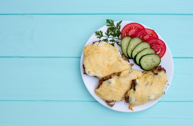 filete con verduras sobre un fondo de madera de color turquesa