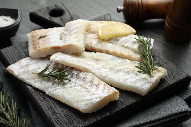 Filetes de bacalao crudos frescos con romero y limón en la mesa de cerca