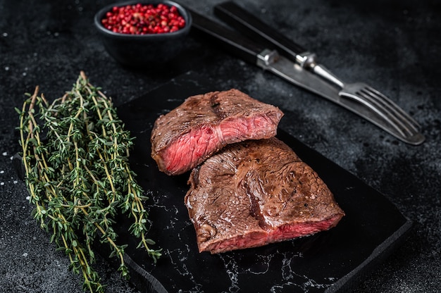 Filetes de carne asada con cuchilla superior o rosbif de hierro plano sobre tabla de mármol