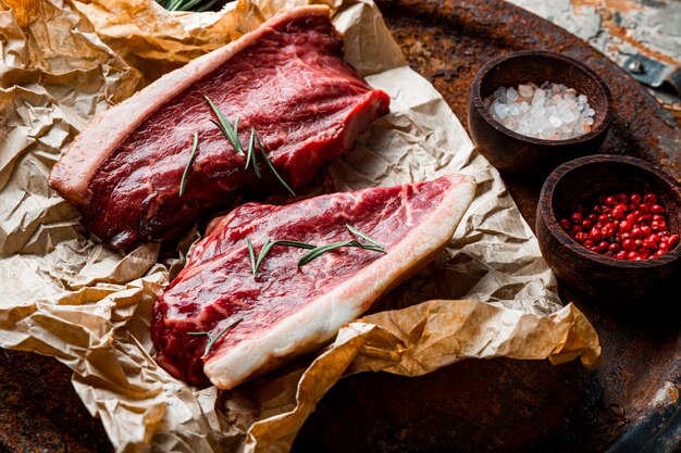 Filetes de carne cruda de mármol y condimentos para su preparación en el fondo de madera vieja. Carne de res cruda en la mesa de la cocina. Foto de alta calidad