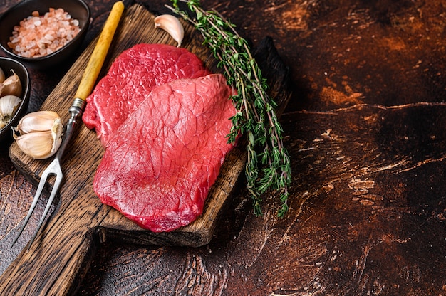 Filetes de carne de ternera cruda en tablero de madera de carnicero