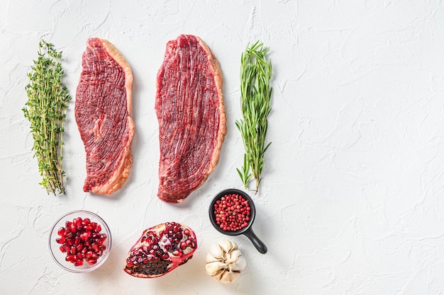 Filetes de carne de ternera picanha orgánica con condimentos sobre fondo de textura blanca vista superior con espacio para texto