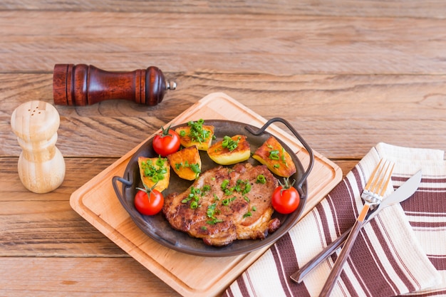 Filetes de cerdo asados en sartén de carne de cuello con patata. fondo de madera.