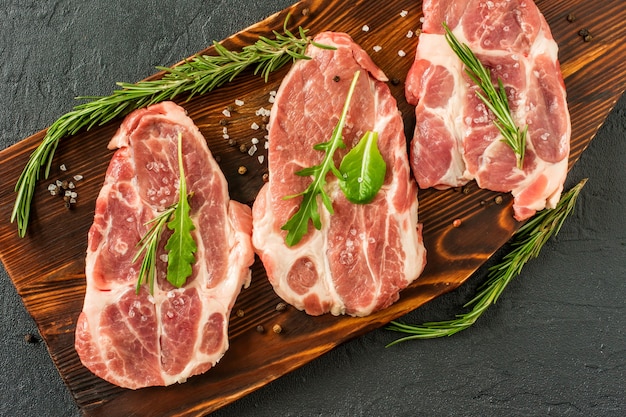 Filetes de cerdo crudos con romero y tomates. Carne de cerdo fresca. Bistec de cuello. Carne ecológica Keto y Paleo Diet.