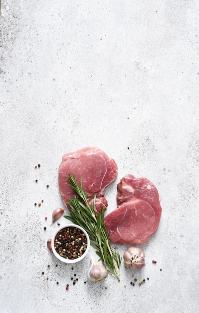 Filetes de cerdo frescos sobre un fondo de hormigón ligero carne cruda con especias en la vista superior de la mesa de la cocina