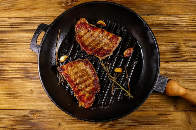 Filetes de cerdo a la parrilla con ajo de romero y especias en una sartén de hierro fundido sobre una mesa de madera Vista superior