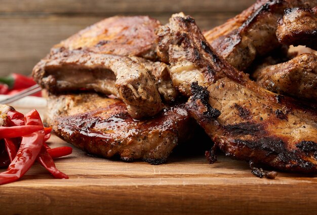 Filetes de cerdo a la parrilla sobre el hueso en una tabla de cortar de cocina y ají rojo