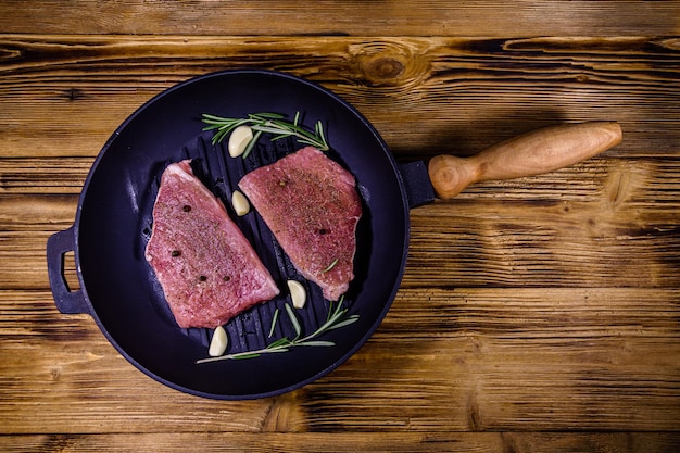 Filetes crudos con ajo, romero y especias en una parrilla de hierro fundido. Vista superior