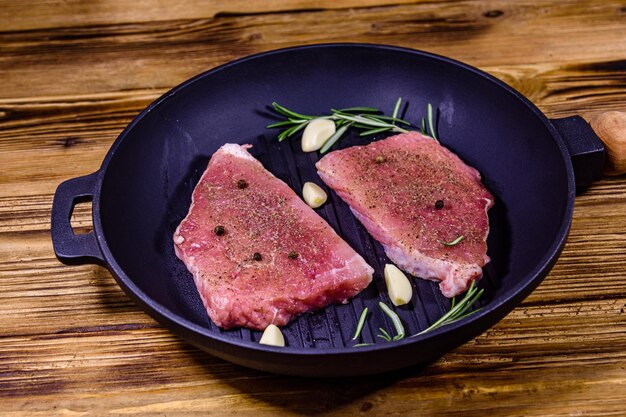 Filetes crudos con ajo, romero y especias en una parrilla de hierro fundido