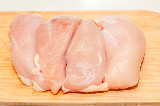 Foto filetes crudos de pechuga de pollo sin piel en una tabla de cortar