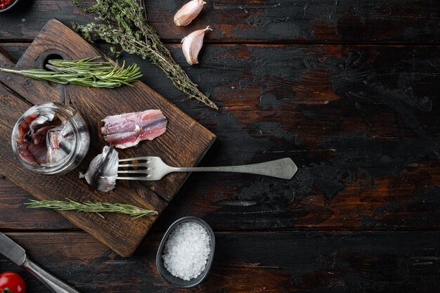 Filetes de anchova salgada, em tábua de madeira, velha mesa de madeira escura