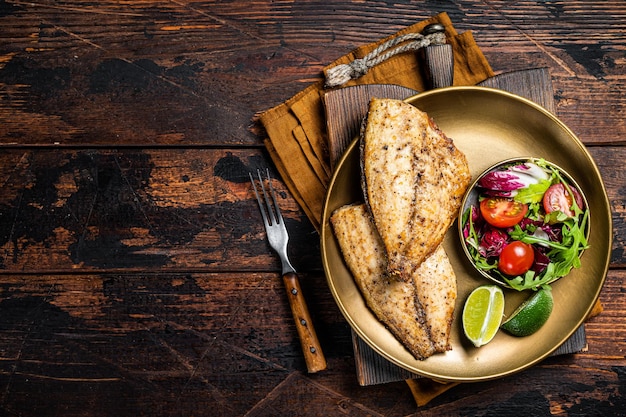 Filetes de Dourada assados servidos com salada de legumes frescos Fundo de madeira Vista de cima Espaço para cópia