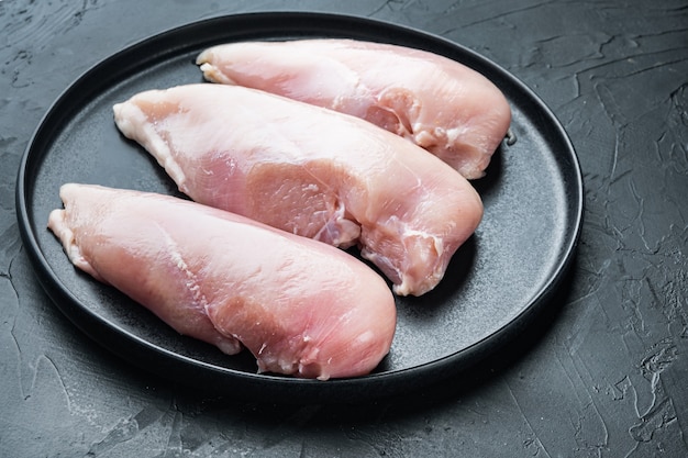 Filetes de frango crus, na mesa preta