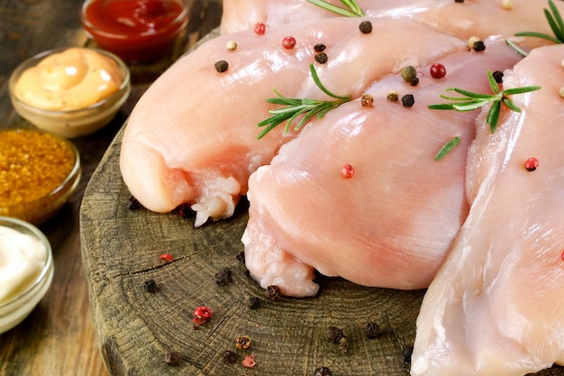 Filetes de peito de frango cru fresco polvilhados com alecrim e molhos de pimenta