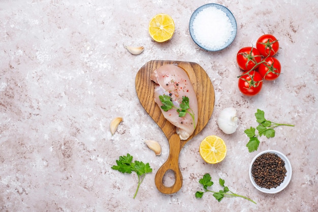 Filetes de peito de frango cru na tábua de madeira com ervas e especiarias. vista superior