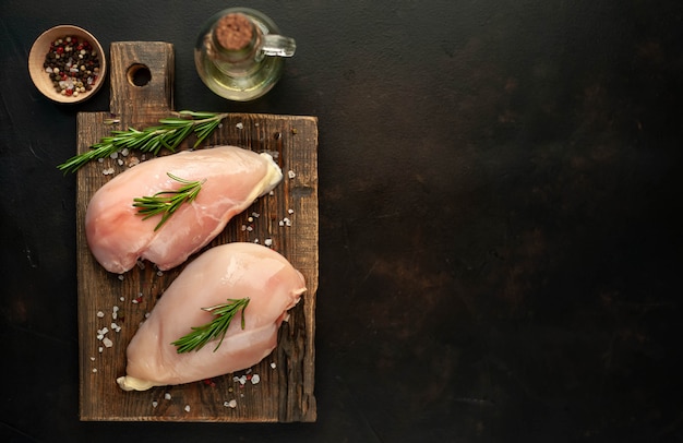 Filetes de peito de frango cru, prontos para cozinhar sobre uma tábua de madeira com especiarias. com espaço de cópia para o seu teste