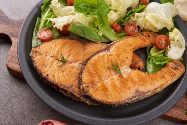 Filetes de salmão cozinhados deliciosos. Filé de salmão grelhado e salada de tomate vegetal com alface verde fresca. Conceito de nutrição equilibrada para uma dieta mediterrânea flexitariana de alimentação limpa.