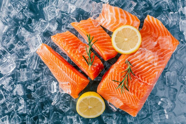 Filetes de salmão fresco no gelo com fatias de limão e guarnição de romário para apresentação culinária