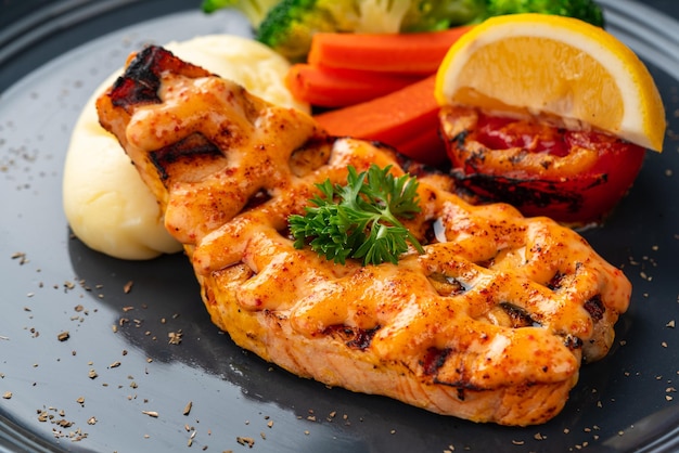 Filetes de salmão grelhado com molho mentai e purê de batata em chapa preta com espaço negativo